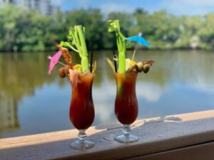 Two glasses of bloody mary cocktails on a ledge.