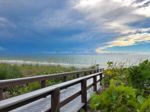 A boardwalk near the ocean with a cloudy sky above.