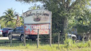 A sign for southern fresh farms in front of a fence.