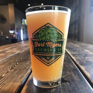 A glass of beer sitting on top of a wooden table.