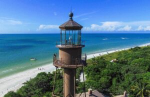 A lighthouse on the beach with people in it.