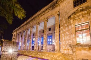 A building with columns and windows lit up at night.