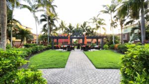 A garden with a gazebo, grills and lawn chairs.