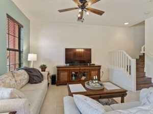 A living room with white furniture and a tv.