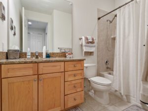 A bathroom with a toilet, sink and mirror.