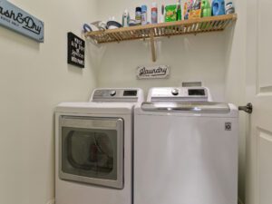 A washer and dryer in a room with a shelf above them.